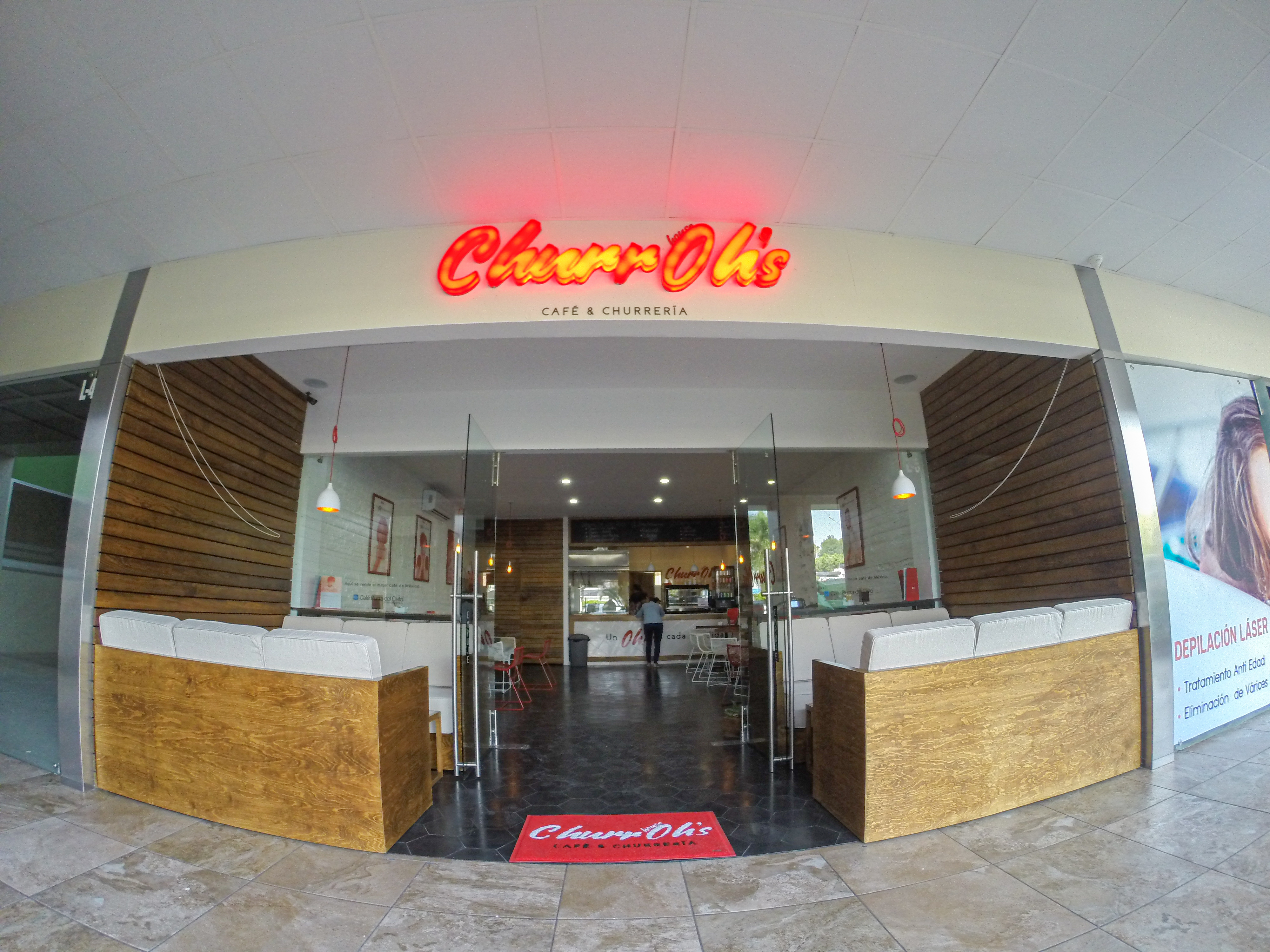 Mostrador y barra de atención de churrería con revestimiento en madera e iluminación cálida, acabados interiores Fer Et Ciment